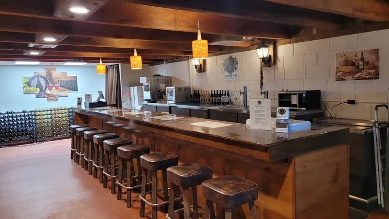 Rustic wood bar with stools and warm pendant lighting inside the speakeasy tasting room at Morton Family Cellars in Apple Hill